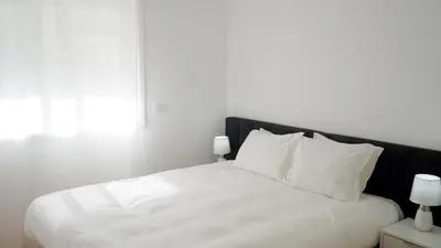 a white bed with white pillows and a black headboard at Gaia Central Apartment in Vila Nova de Gaia