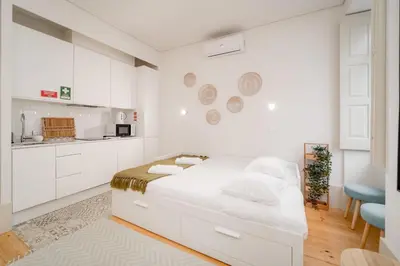 a white room with a bed and a kitchen at Nomad's Bonjardim City Flats in Porto