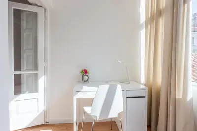 a white desk with a white chair next to a window at Alves da Veiga Apartments in Porto