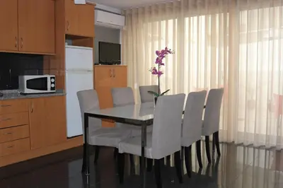a dining room table with white chairs and a vase of flowers at Studios Porto Solar in Porto
