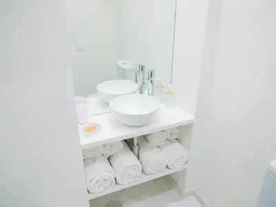 a white bathroom with a sink and toilet paper at CM VINTAGE Apartments - Breiner in Porto