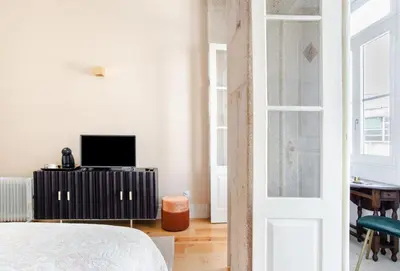 a white room with a bed and a television at Get a Golden and Flower Flat in Porto