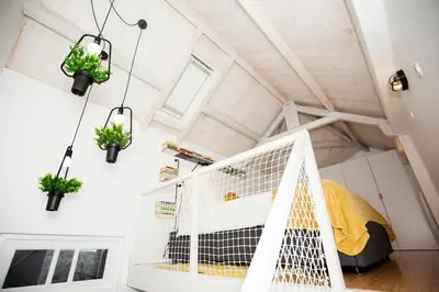 a loft conversion with a bed and potted plants at GET a Cactus and Books studio in Porto