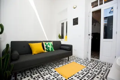 a living room with a couch and a yellow rug at GET a Cactus and Books studio in Porto
