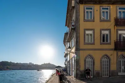 a group of people standing next to buildings next to a river at Porto Premium River View I in Porto