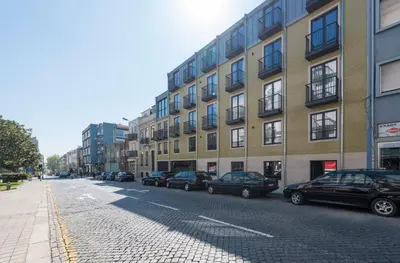a street with cars parked in front of a building at LovelyStay - Downtown Balcony Apartment with Free Parking in Porto