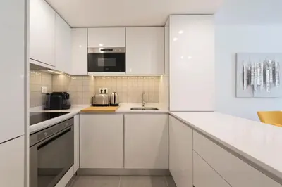 a white kitchen with white cabinets and a sink at LovelyStay - Downtown Balcony Apartment with Free Parking in Porto