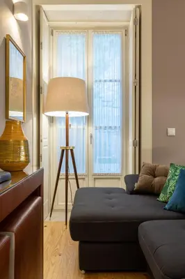 a living room with a couch and a lamp at Porto Garden Studio - Santa Catarina in Porto