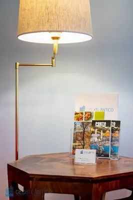 a table with a lamp and a magazine on it at Porto Garden Studio - Santa Catarina in Porto