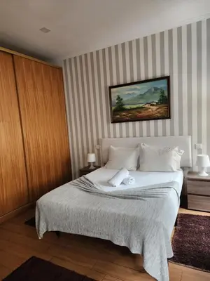 a bedroom with a white bed with a striped wall at D'OURO DONA MARIA By LW in Vila Nova de Gaia