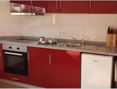 a kitchen with red cabinets and a sink at D'OURO DOM MANUEL By LW in Vila Nova de Gaia