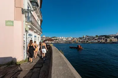 a group of people walking down a sidewalk next to the water at Porto Premium River View II in Porto