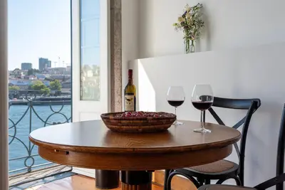 a table with two glasses of wine and a bowl of grapes at Porto Premium River View II in Porto