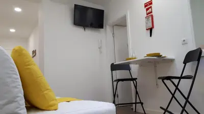 a room with a bed and a table and stools at TMB (Train / Metro& Bus ) Oporto Station House in Porto