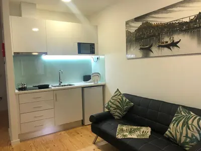 a living room with a couch and a kitchen at TMB (Train / Metro& Bus ) Oporto Station House in Porto