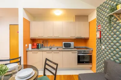 a kitchen with white cabinets and a table with chairs at Cedofeita Paradise w parking included in Porto