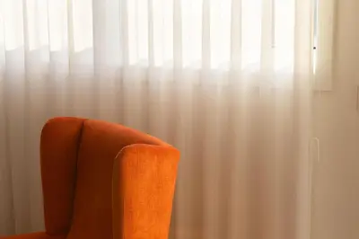 an orange chair sitting in front of a window at LovelyStay - Penthouse Balcony Apartment in Porto