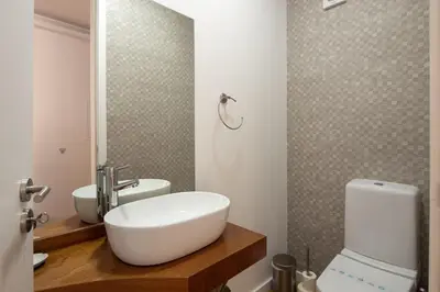a bathroom with a sink and a toilet and a mirror at LovelyStay - Penthouse Balcony Apartment in Porto