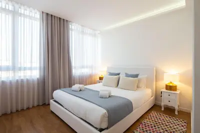 a white bedroom with a large bed with white pillows at LovelyStay - Penthouse Balcony Apartment in Porto