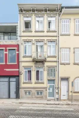 a tall yellow building with windows and a balcony at SwissPorto Guest House in Porto