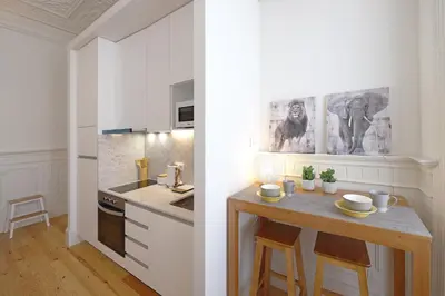 a kitchen with white cabinets and a table with stools at FLH Living Oporto Lofts in Porto