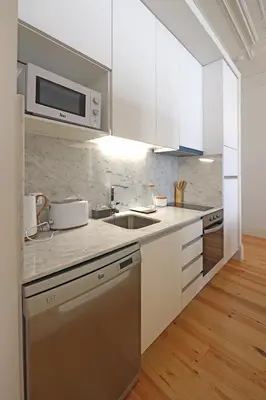 a kitchen with white cabinets and a sink and a microwave at FLH Living Oporto Lofts in Porto