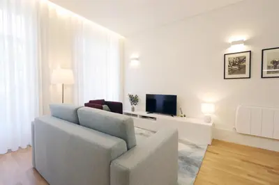 a white living room with a couch and a television at HM - Oporto Cedofeita 500E in Porto