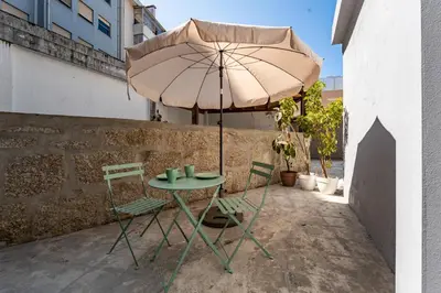 a table and chairs under an umbrella on a patio at Nomad's Boulevard Bonfim Porto in Porto