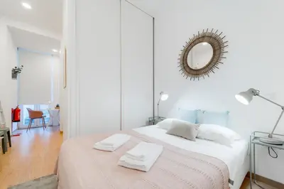 a white bedroom with a bed and a mirror at Nomad's Boulevard Bonfim Porto in Porto
