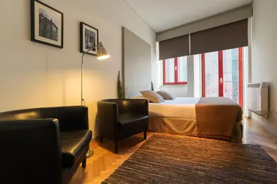a bedroom with a bed and two chairs and a window at bnapartments Trindade in Porto
