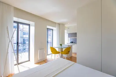 a white bedroom with yellow chairs and a table at Casa São Lázaro by Oporto Soul in Porto