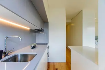 a kitchen with a stainless steel sink and white cabinets at Casa São Lázaro by Oporto Soul in Porto