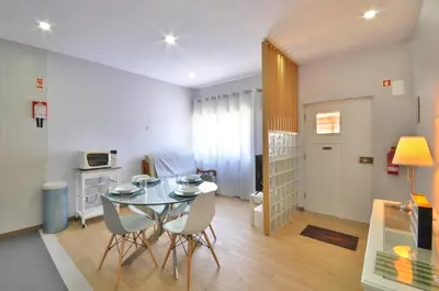 a small kitchen with a glass table and white cabinets at Jardim do Pilar T1 in Vila Nova de Gaia