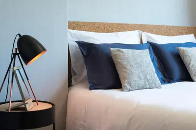 a bedroom with a bed with blue pillows and a lamp at CN150 boutique studio, charming flat in Porto