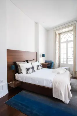 a bedroom with a large bed and a blue rug at D'Autor Apartments Alegria in Porto