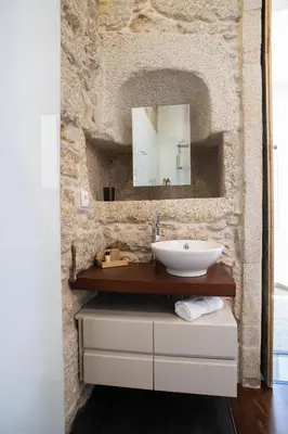 a bathroom with a sink and a stone wall at D'Autor Apartments Alegria in Porto