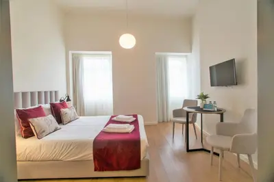 a bedroom with a bed and a table and a tv at Clérigos Prime Suites by Porto City Hosts in Porto