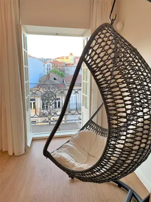 a hammock chair in a room with a window at Clérigos Prime Suites by Porto City Hosts in Porto