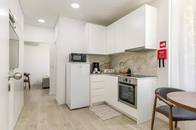 a small kitchen with white cabinets and a table at Bra.com Apartments Oporto Faria Guimarães in Porto