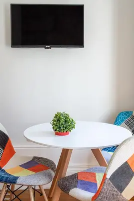 a white table with chairs and a tv on a wall at ZD Moreira Flats B By PortoProperties4You in Porto