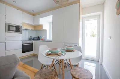 a white kitchen with a white table and chairs at Porto Insight Apartments Campanhã in Porto