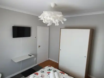 a bedroom with a bed and a television and a chandelier at Ninho Jardim do Morro in Vila Nova de Gaia