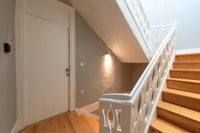 a white staircase with a blue chair next to a door at Cedofeita Deluxe Apartment 3B in Porto
