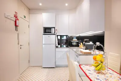 a kitchen with white cabinets and a table with bananas on it at Refugio in Porto