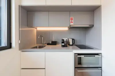 a kitchen with white cabinets and a sink at LovelyStay - Gorgeous Modern Flat w/ Balcony in Porto