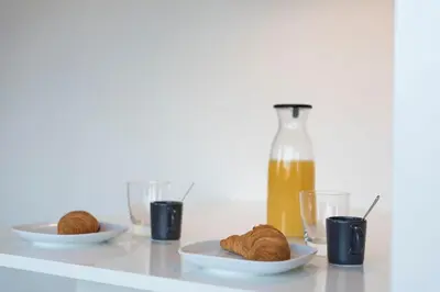 a table with plates of food and a bottle of orange juice at LovelyStay - Gorgeous Modern Flat w/ Balcony in Porto