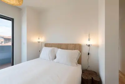 a bedroom with a bed with white sheets and a window at LovelyStay - Gorgeous Modern Flat w/ Balcony in Porto