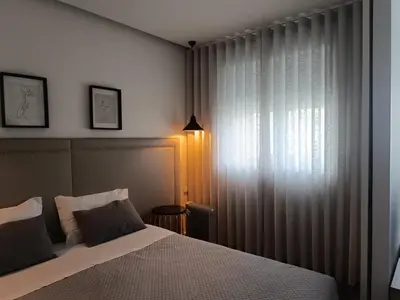 a bedroom with a bed and a window with curtains at Angel Flats in Porto