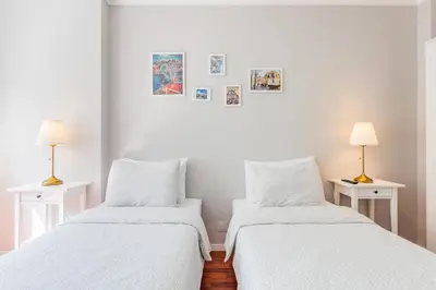 two beds in a room with white walls and lamps at Apartamento Lar doce Lar Porto in Vila Nova de Gaia
