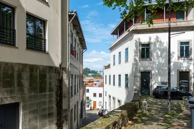 an alley between two buildings with a car parked on the street at Marias River Apartment in Porto